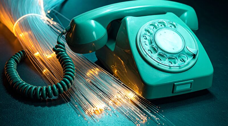 Vintage rotary telephone with glowing fiber optic cables representing modern VoIP and Asterisk telephony